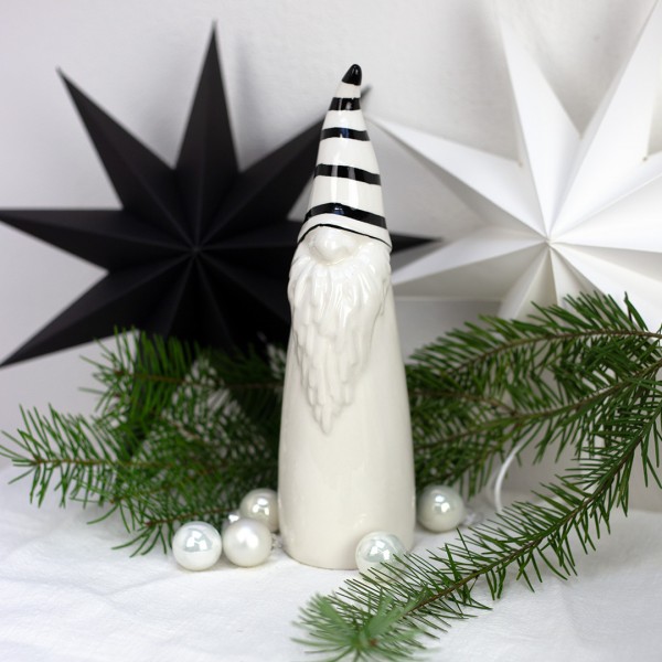Keramik Wichtel | groß mit schwarz-weiß gestreifter Mütze und Weihnachtsdeko im Hintergrund