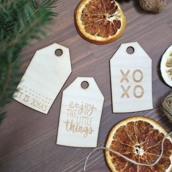 drei Anhänger mit verschiedenen Sprüchen zwischen Weihnachtsdeko