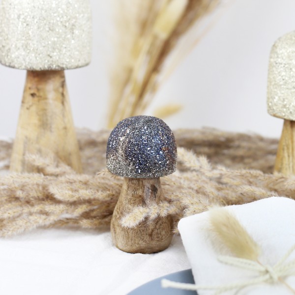kleiner Pilz aus Holz mit schwarzen Glitzer Hut und Trockenblumen im Hintergrund